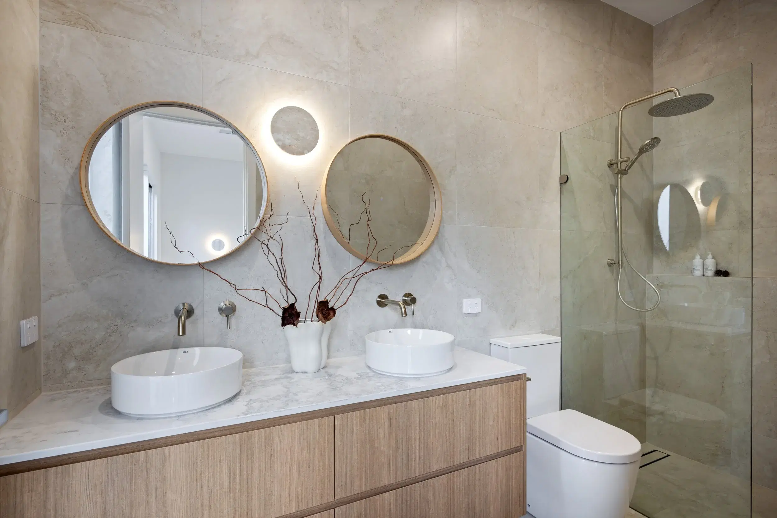 Bathroom with double timber vanity, round mirrors and glazed shower