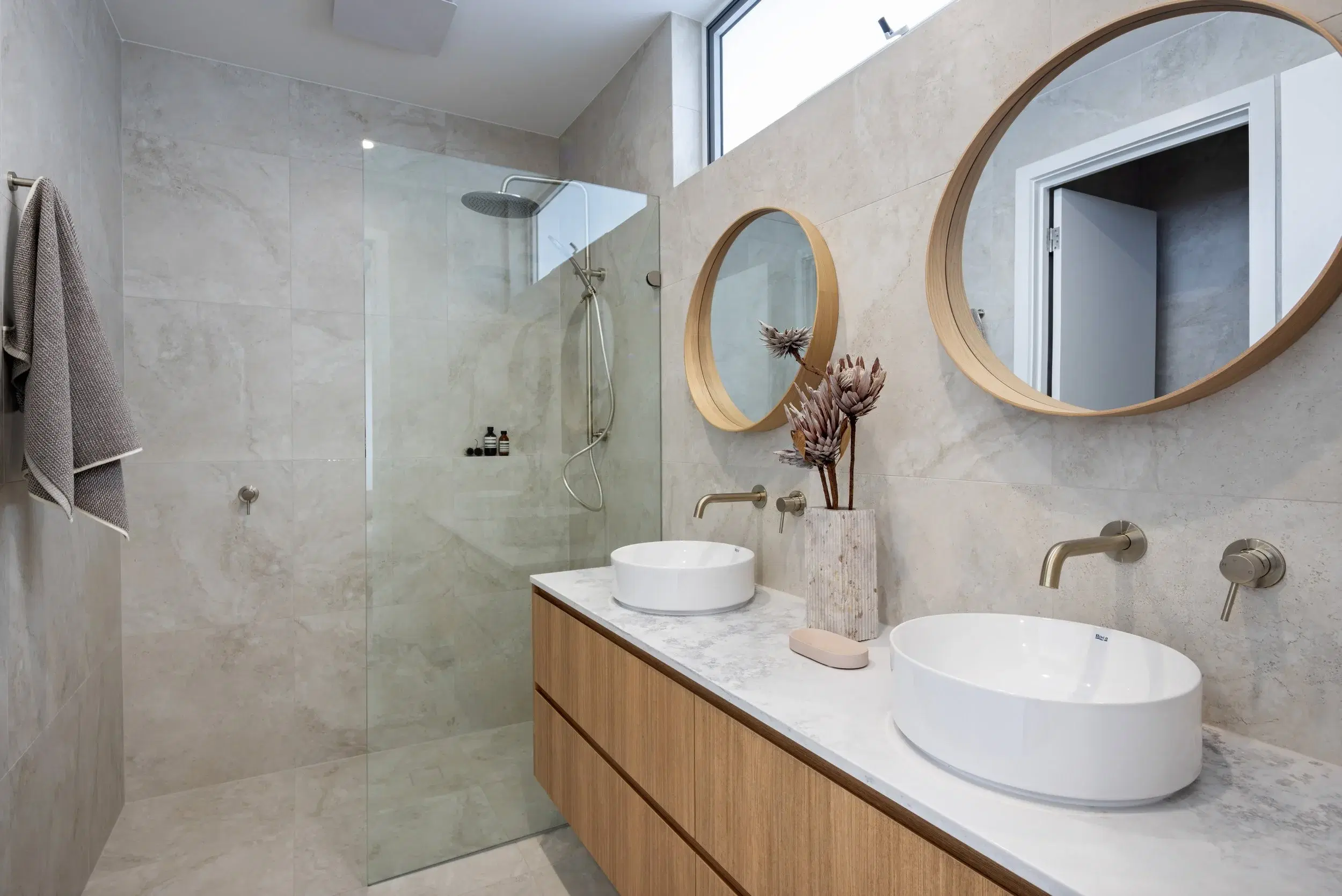 Double bathroom vanity with timber cabinetry and two round mirrors