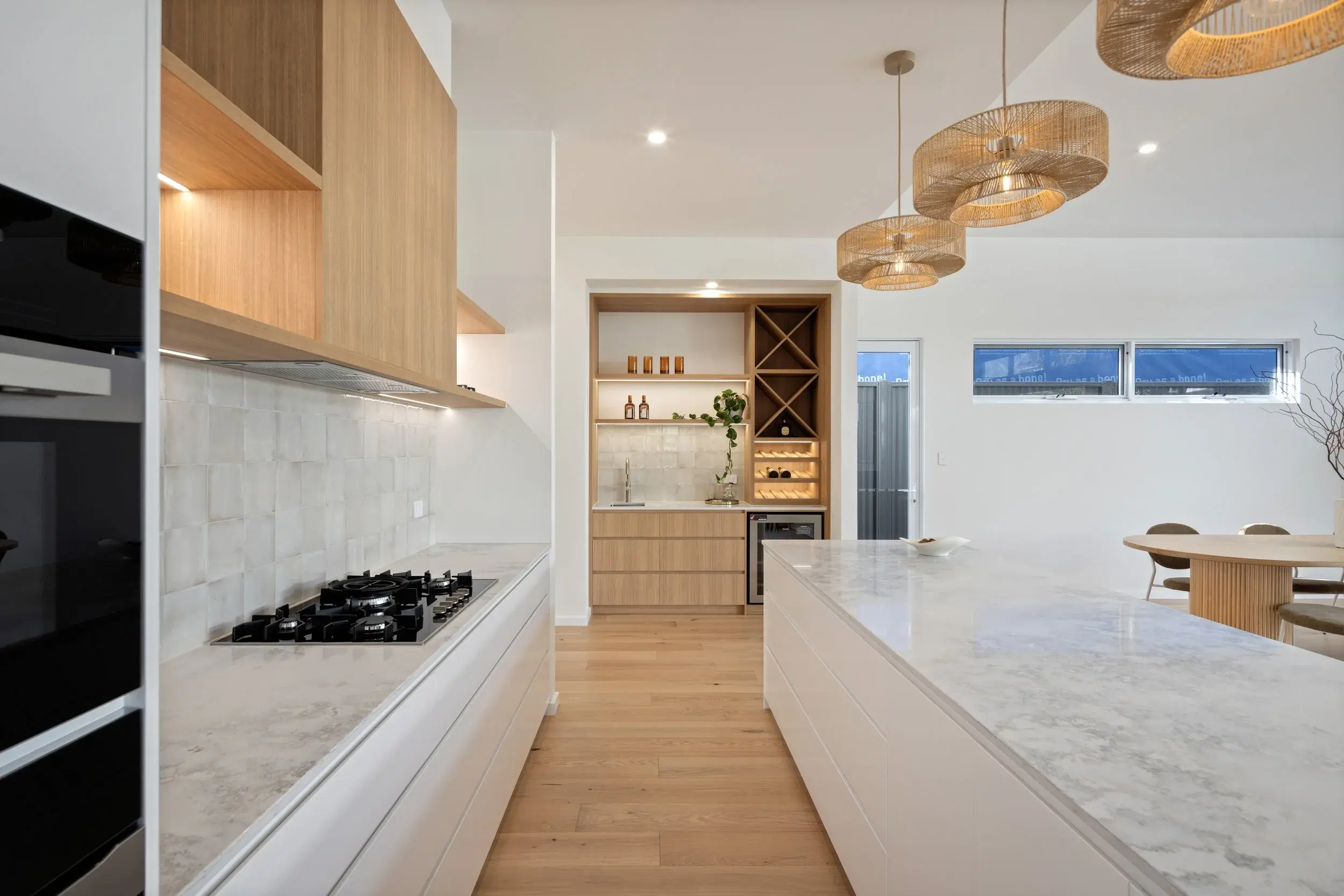 White and timber kitchen with long stone island and integrated bar joinery